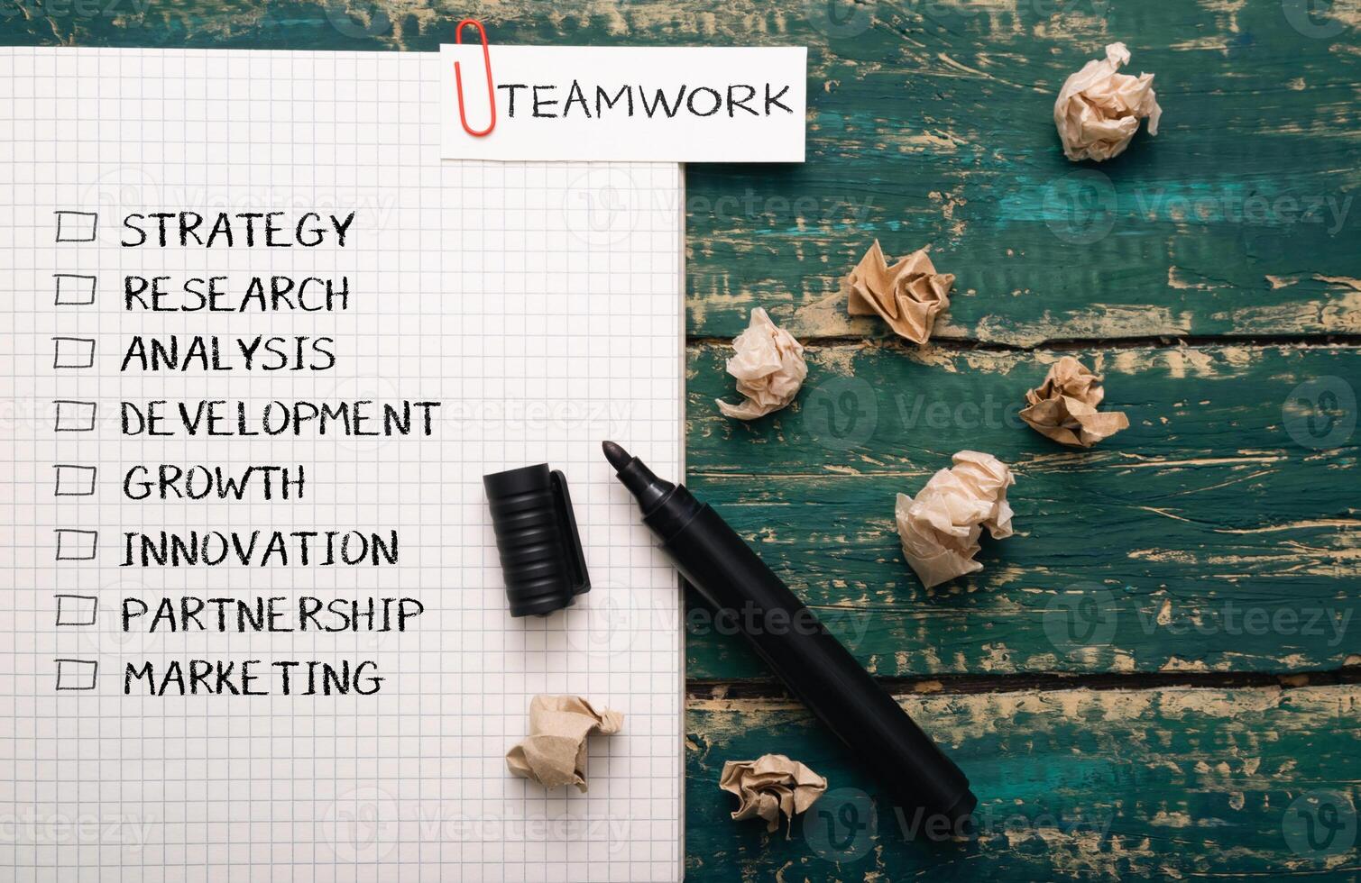 Piece of paper with a black marker on it with the word teamwork written in red photo