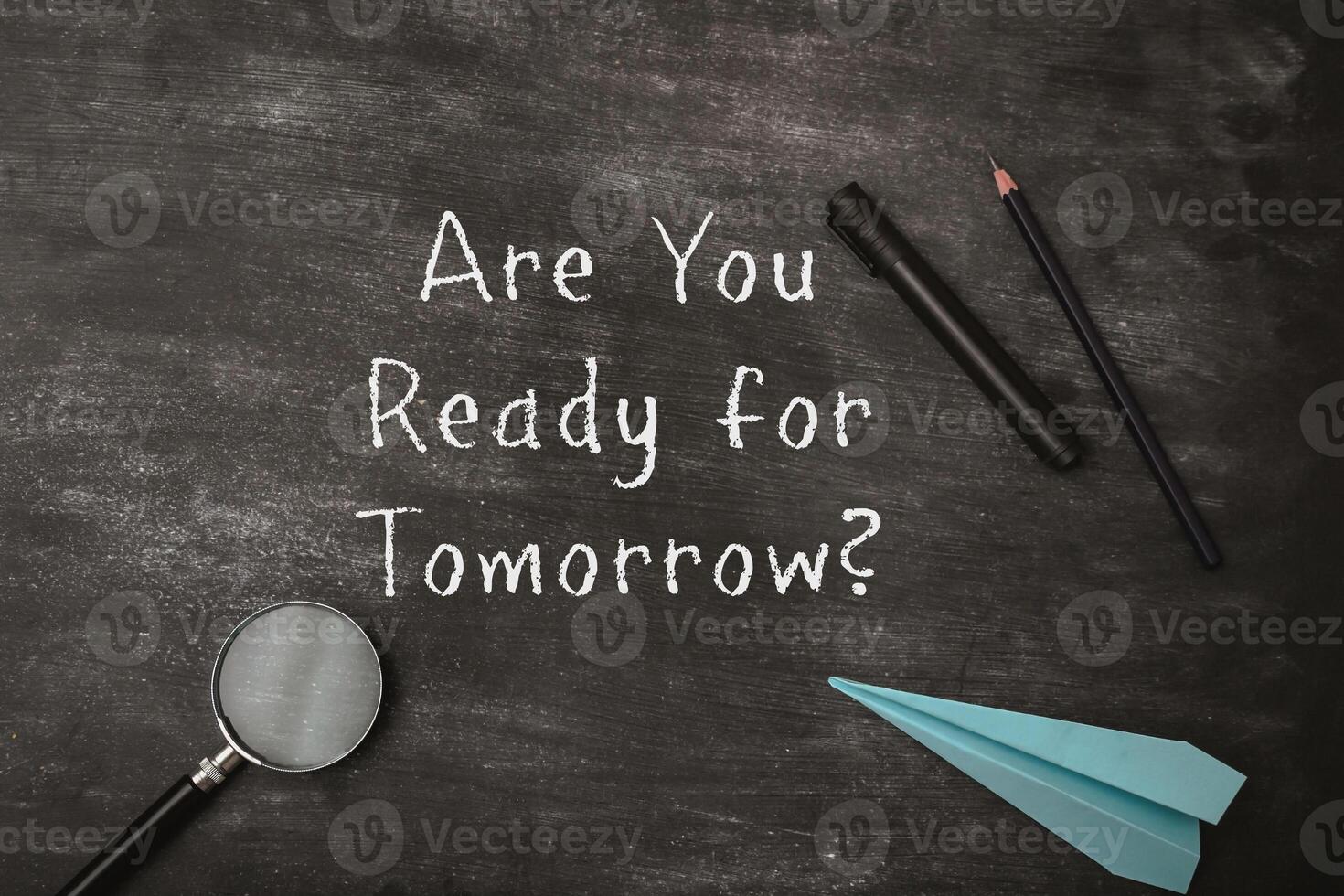 A chalkboard with a magnifying glass, pencils, and a paper airplane on it photo
