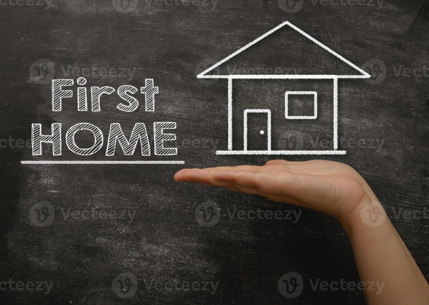 Hand holding a chalkboard with the words First Home written on it photo