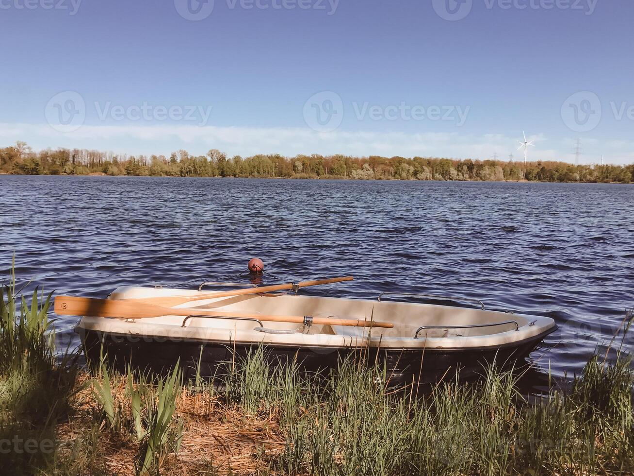 A small boat sits in the water with a paddle in the front photo