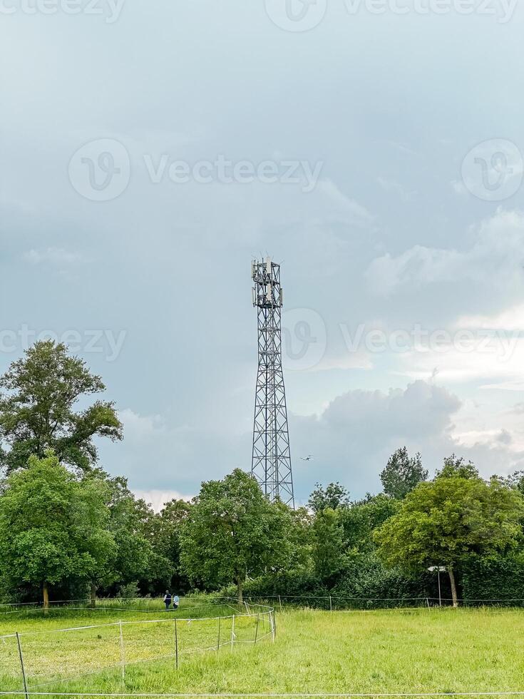 Tall tower with a cell phone antenna on top stands in a field photo