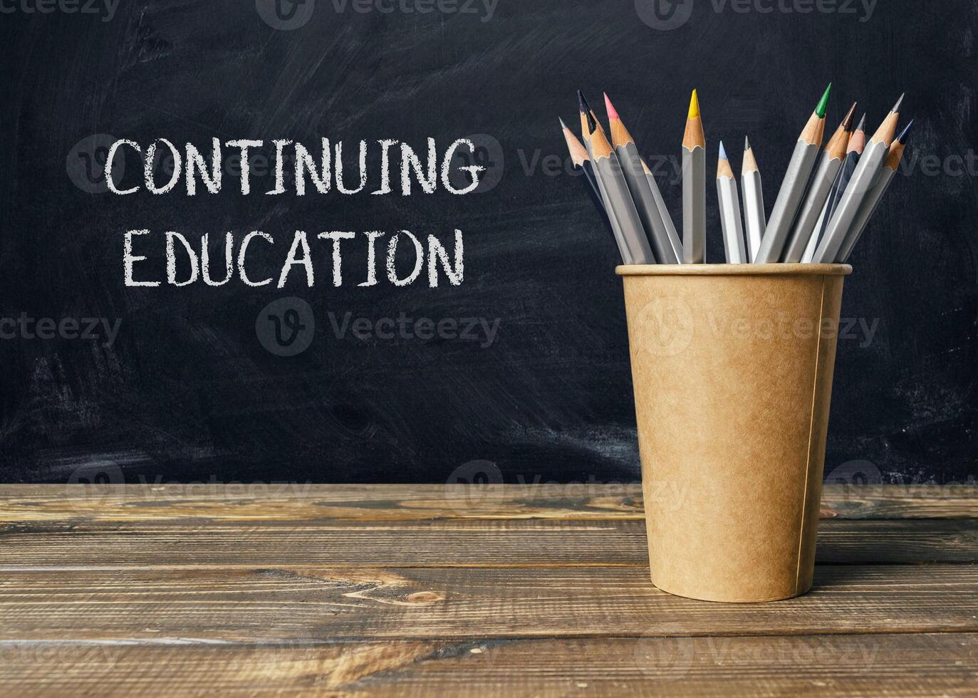 A wooden table with a brown cup of pencils photo