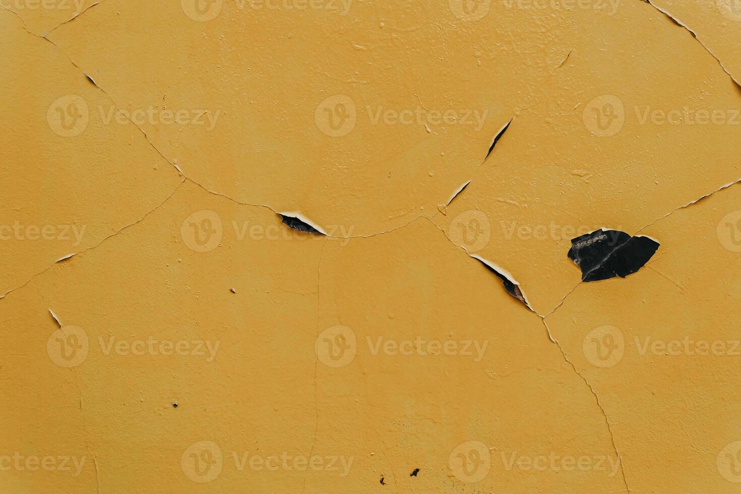 A yellow wall with a crack in it and a leaf on it photo