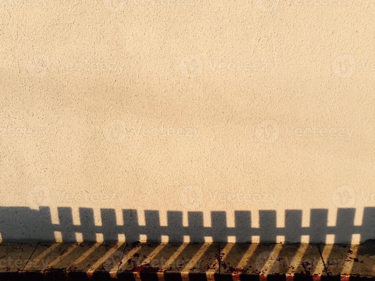 A fence casts a shadow on a wall photo