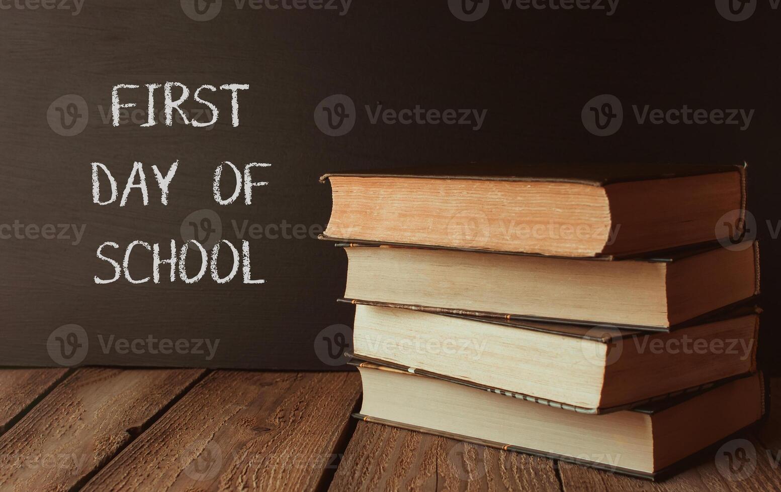 A stack of books with the words First Day of School written on a chalkboard photo