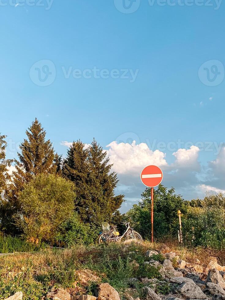Red and white sign with a white line in the middle is on a hillside photo