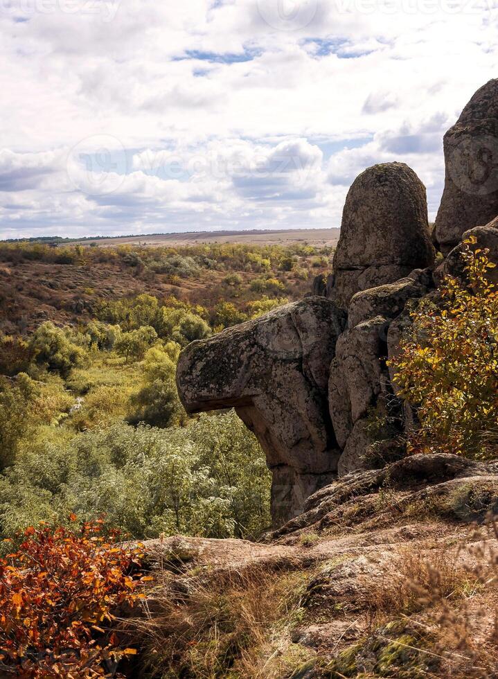 fantastic autumn in a mountain canyon, huge rocks. big gray granite boulders on the top of the mountain, stone figures. yellow and red trees grow among the rocks. Aktovsky Canyon, Ukraine with rocks. photo