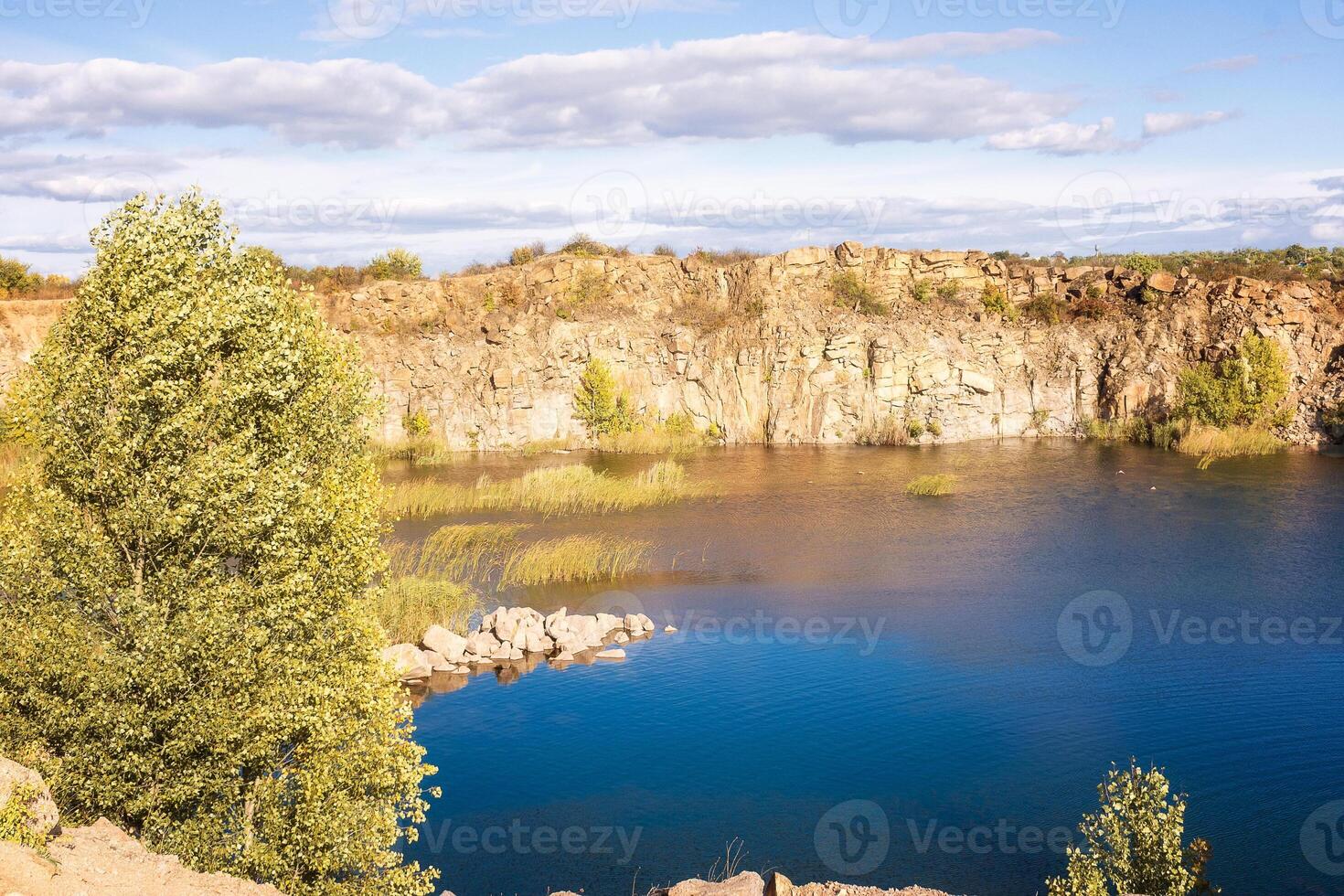 fantastic autumn in a mountain canyon. huge granite boulders around a huge bright blue lake, the lake and rocks are illuminated by the sun. Aktovsky canyon in Ukraine with cliffs. photo