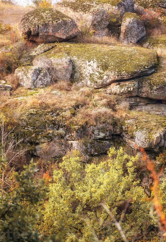 fantastic autumn in a mountain canyon, huge rocks. large gray granite boulders on top of a mountain, stone steps. yellow and red trees grow among the rocks. Aktovsky Canyon, Ukraine and mountains. photo