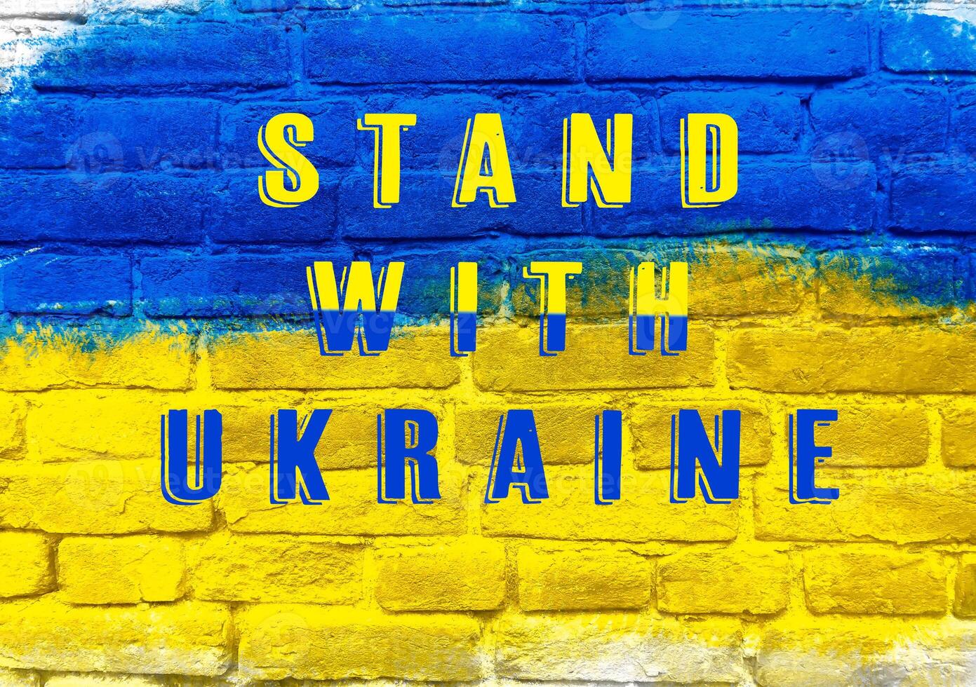 A blue and yellow brick wall with the words Stand with Ukraine written on it photo