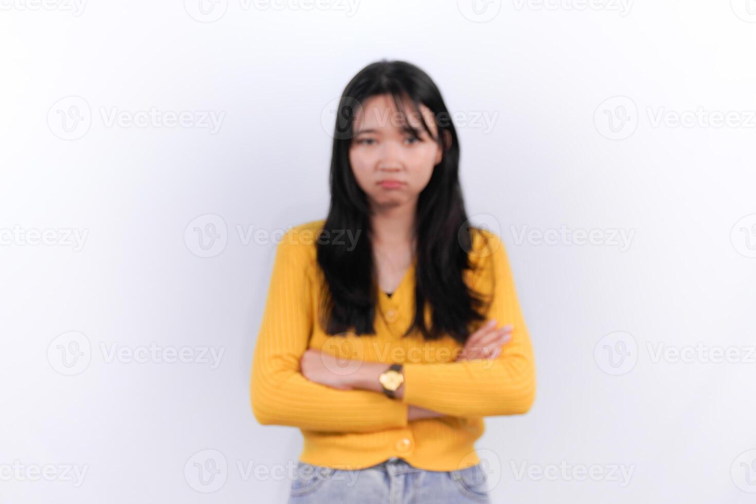 a woman in a yellow sweater standing with her arms crossed photo