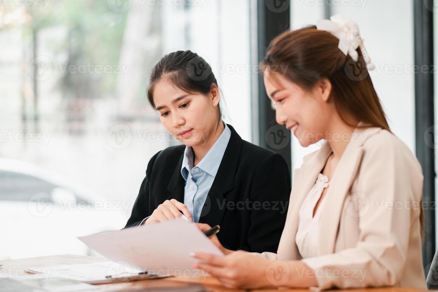 Two women in a business meeting, discussing documents in a bright, modern office environment. photo