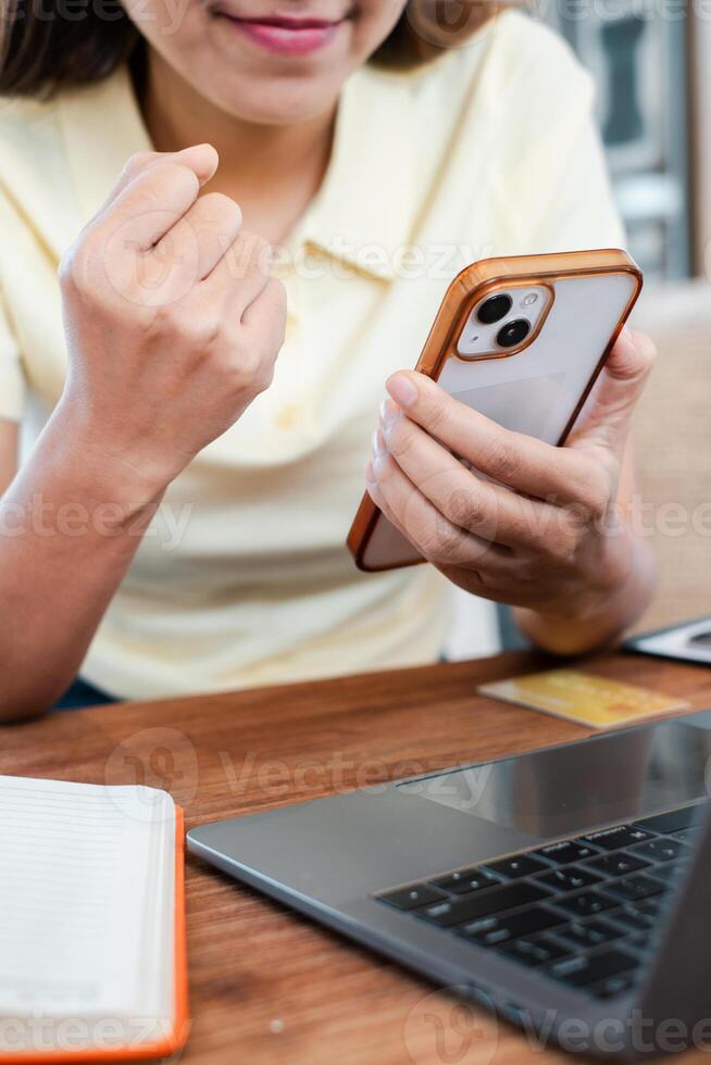 A woman in a casual setting using a smartphone and laptop, showcasing modern technology in daily activities. photo
