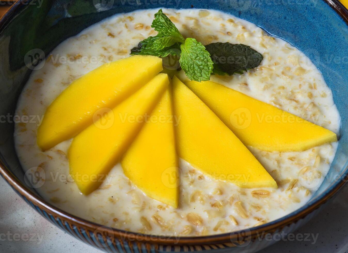Oatmeal served with mango on wooden table close up photo