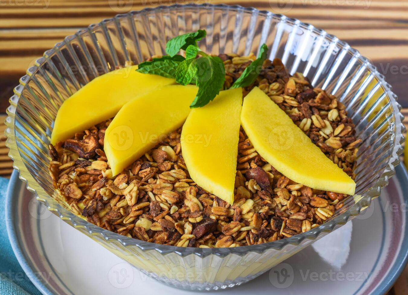 Granola served with mango on wooden table close up photo