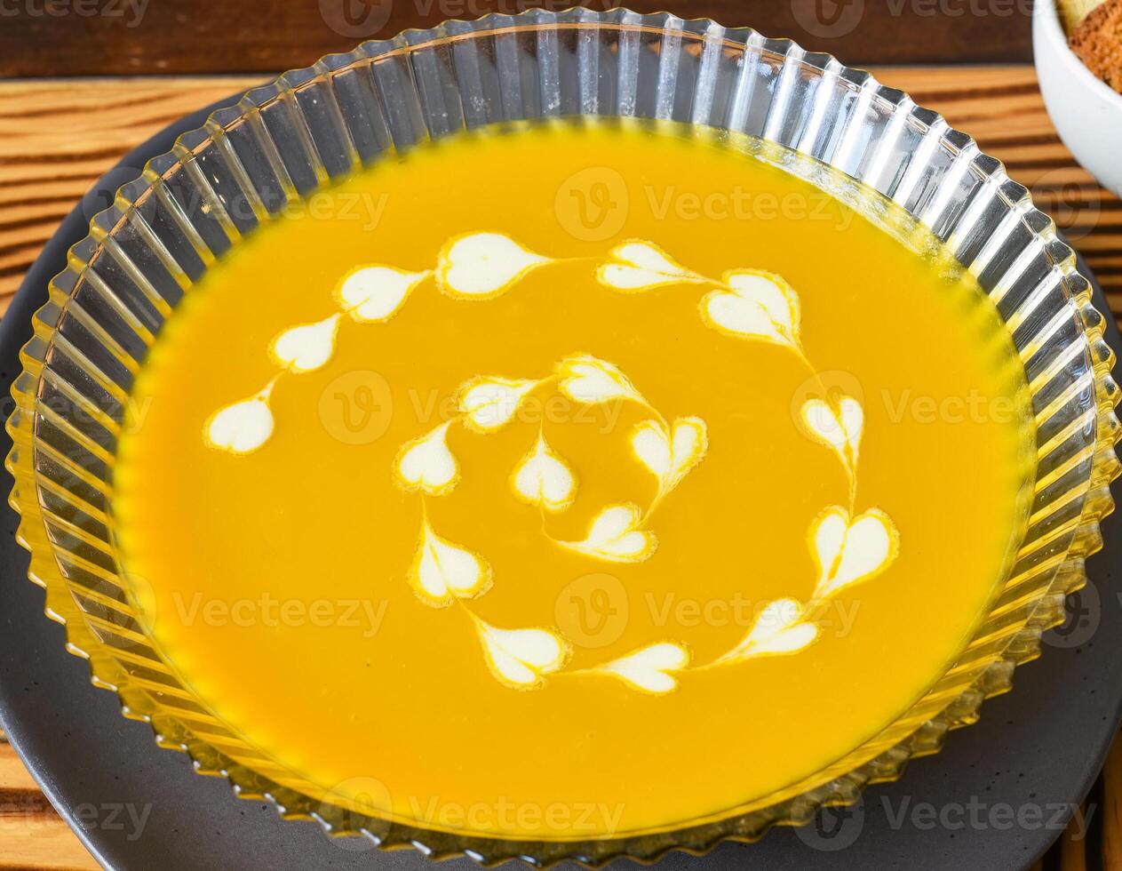 Pumpkin Soup on wooden table with crackers side views photo