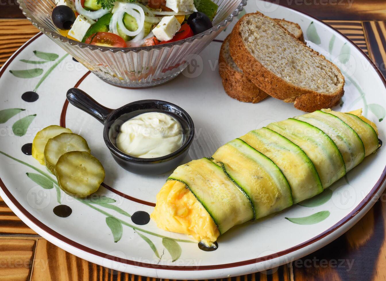 Zucchini omelette with fresh salad bread and sauce on a plate on wooden table photo