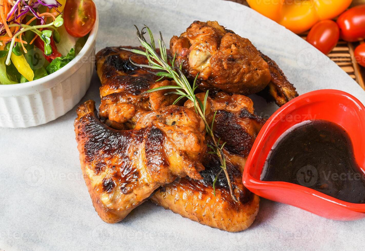 Fried chicken wings served vegetable sauce and sauce on a white plate close up side view photo