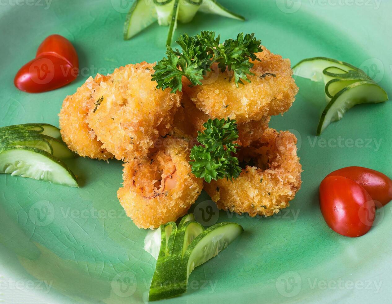 Fried squid or calamari in batter on a green plate close up side view. photo