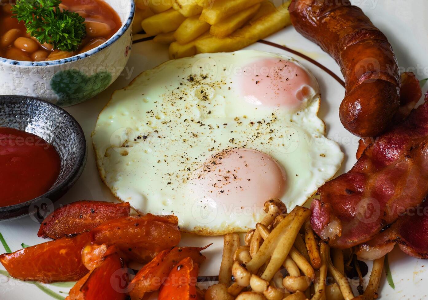 Healthy english breakfast with fried eggs, sausages, bacon, french fries, bean and tomatoes close up photo