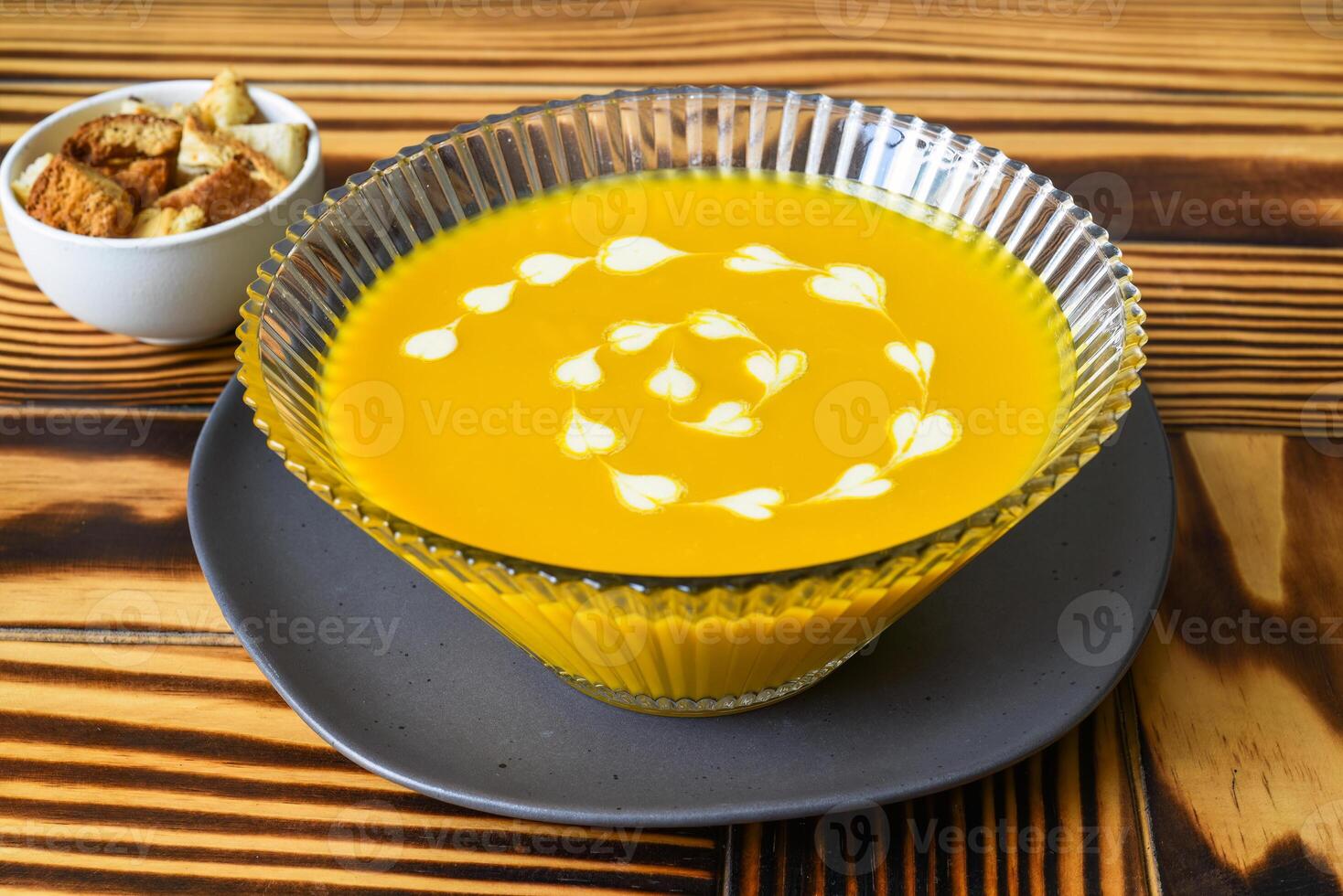 Pumpkin Soup on wooden table with crackers side views. photo
