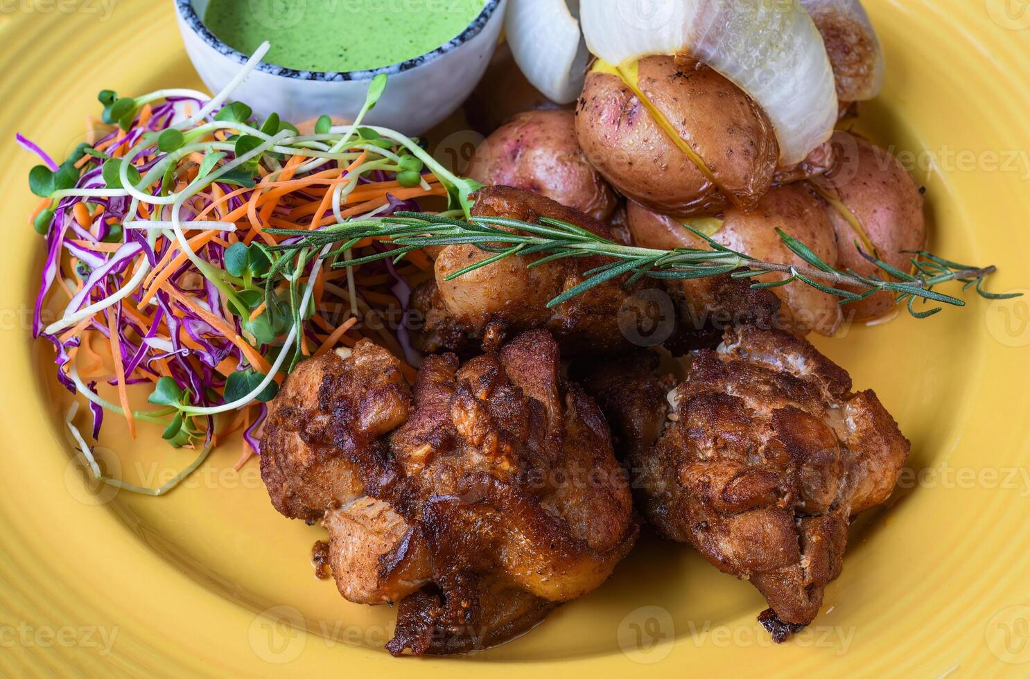 Peruvian Chicken with Green Sauce and salad with potato on a yellow plate close up side view photo
