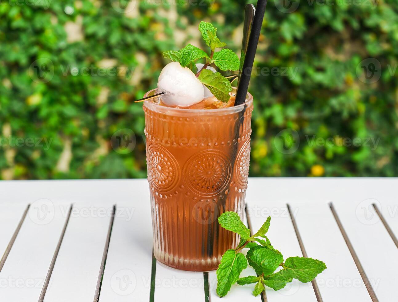 Ice green tea with lychee and mint on a white wooden table against green leaves with copy space photo