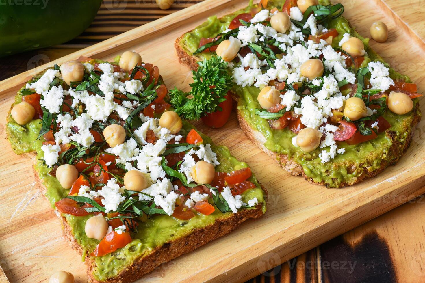 Vegetarian classic avocado toasts with tomato tofu cheese on wooden board photo
