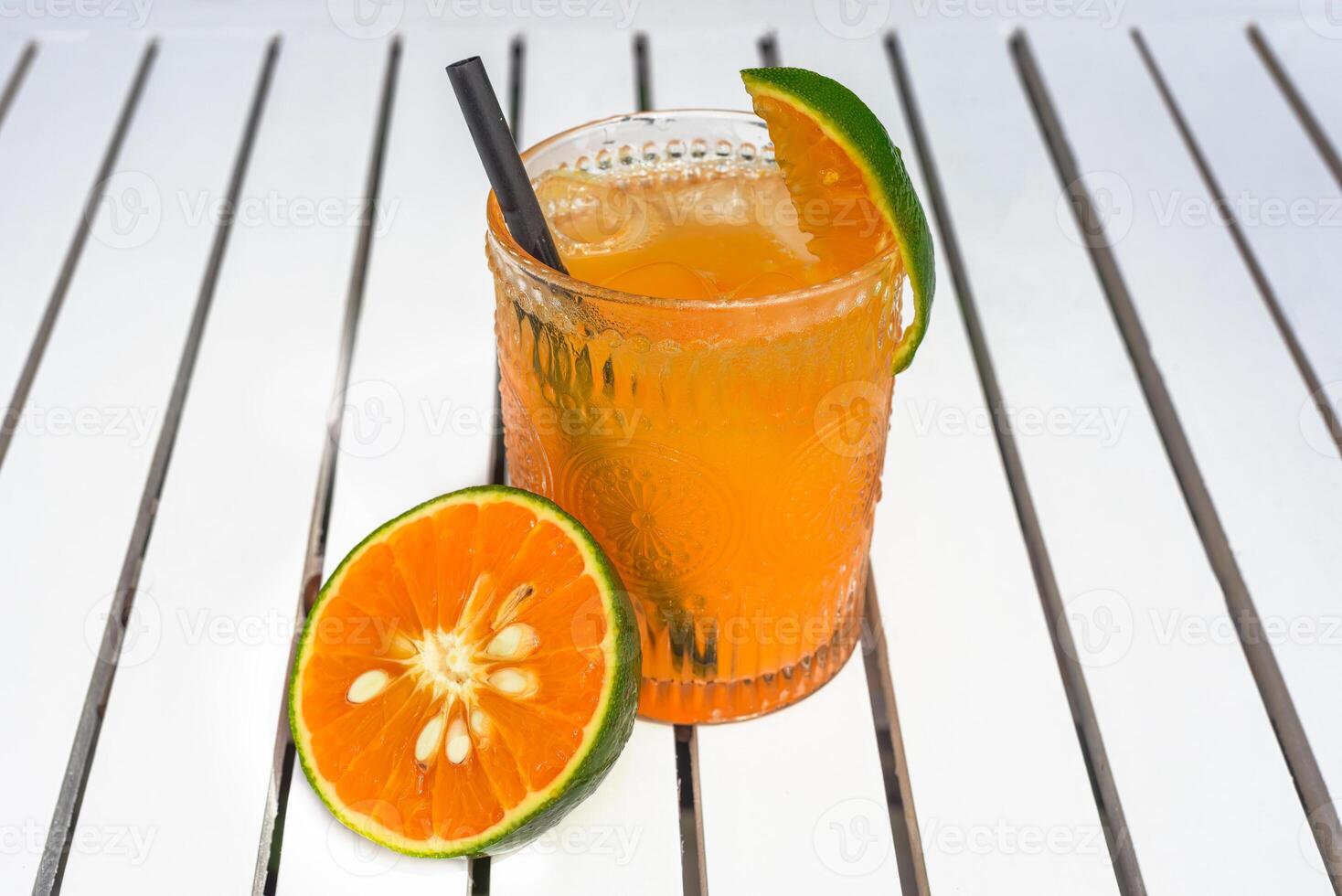 Orange juice with ice on the white wooden table with slice of orange and copy space photo