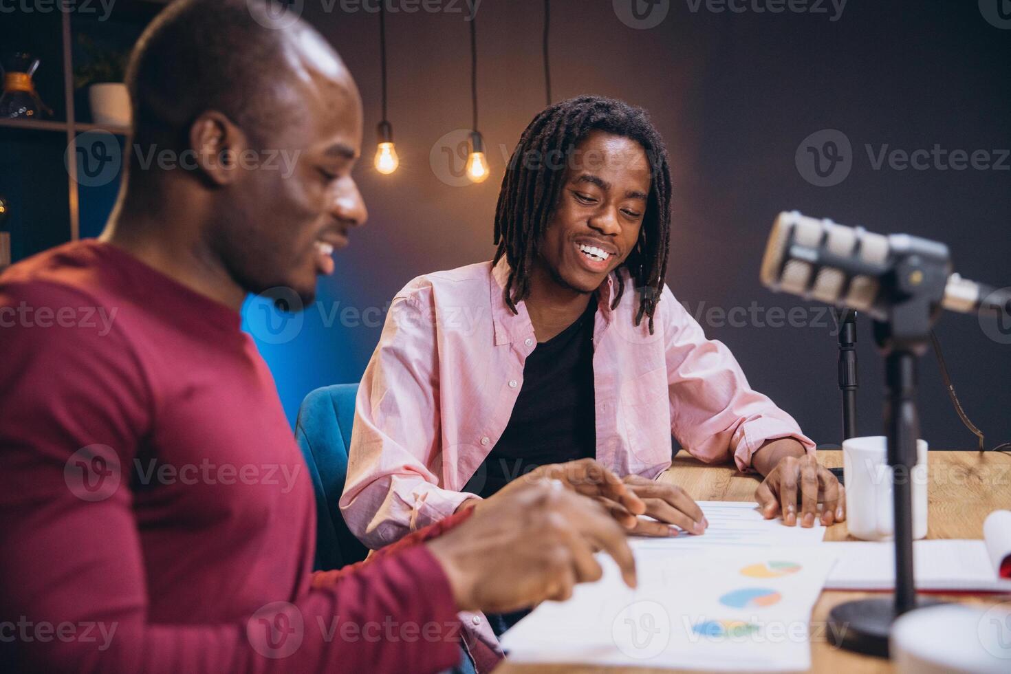 Podcasters discussing data visualizations during collaborative recording session in contemporary broadcasting workspace photo
