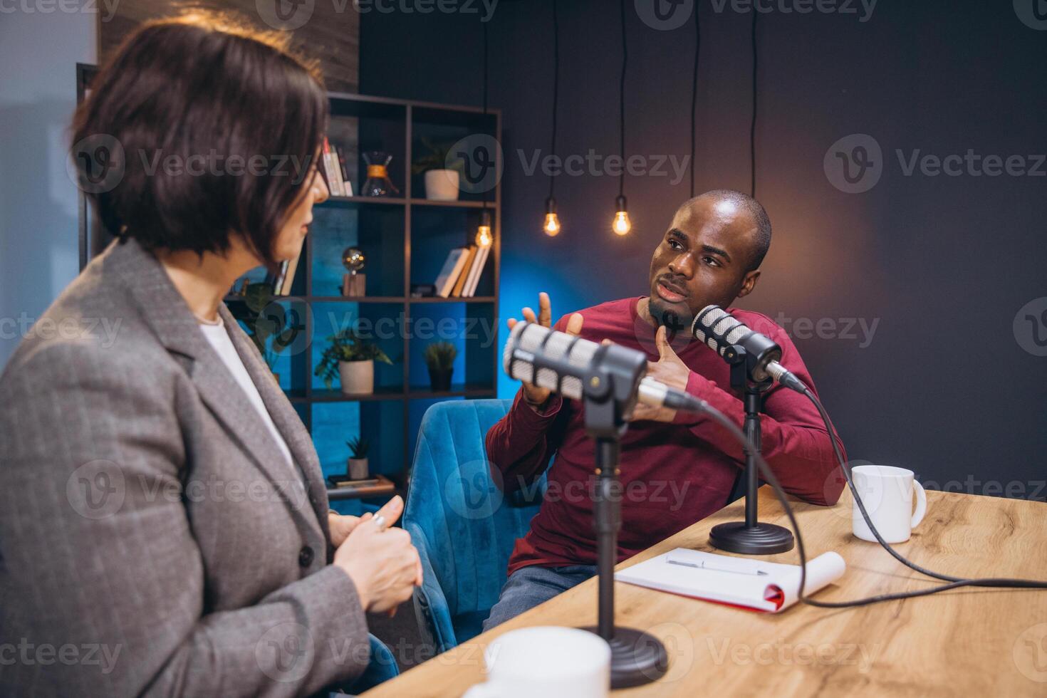 Two diverse podcasters engaging in a discussion while recording their show in a professional studio photo