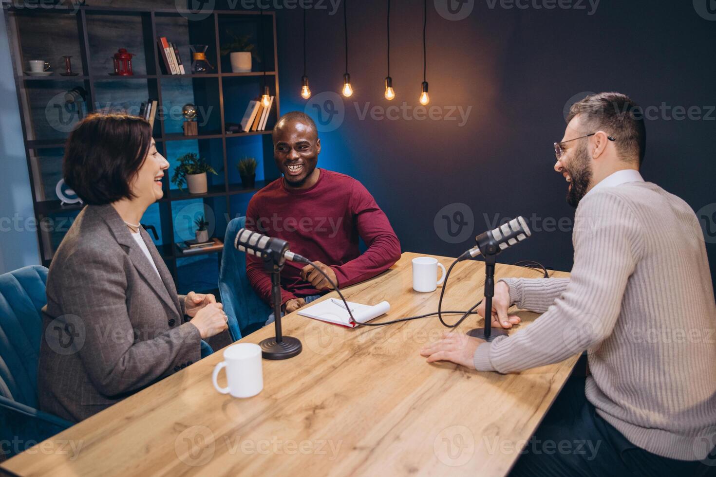Podcasters laughing, connecting during studio recording session with sleek microphones and professional audio gear photo