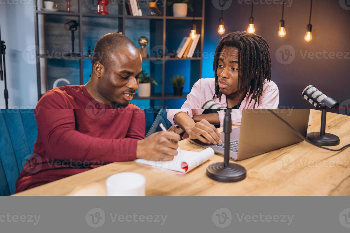 African American podcasters recording conversation, sharing insights, collaborating at professional audio setup with microphones and sound equipment photo