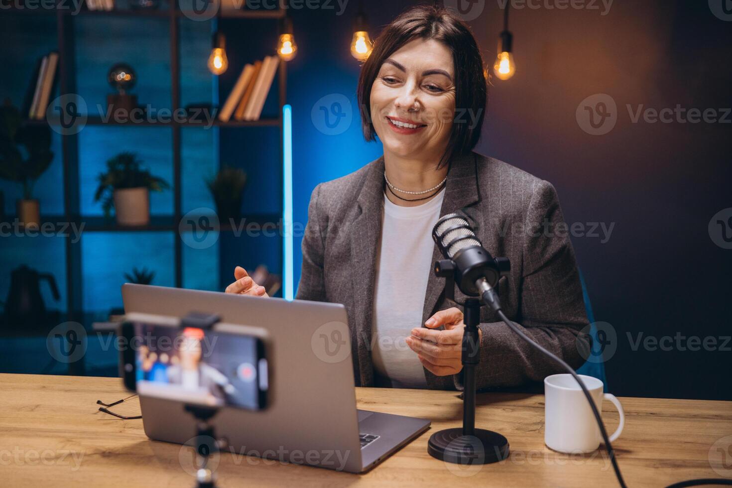 Professional female podcaster speaking into microphone, recording multimedia content while working from home recording studio photo