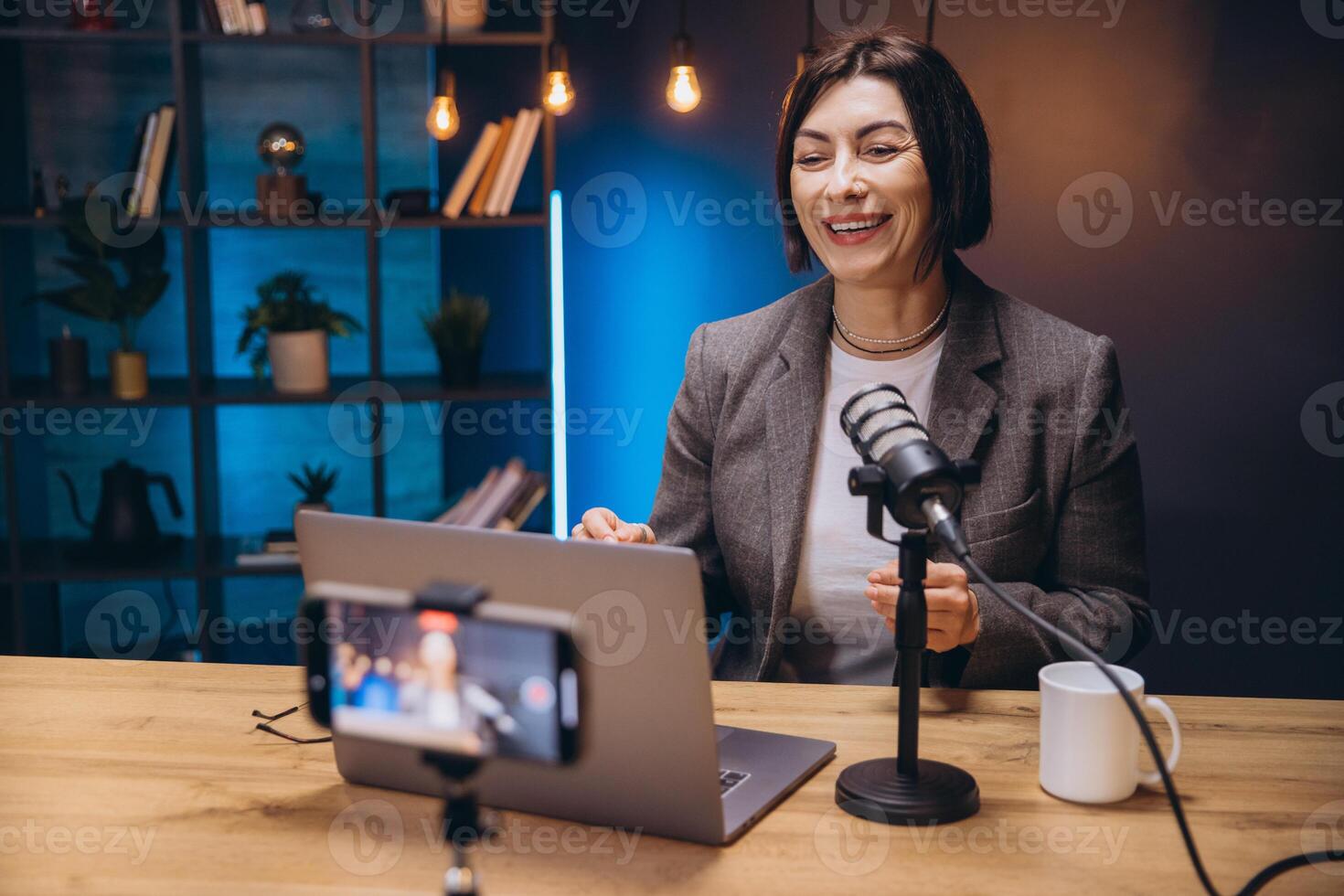 Smiling female podcaster speaking into microphone during professional audio recording session photo