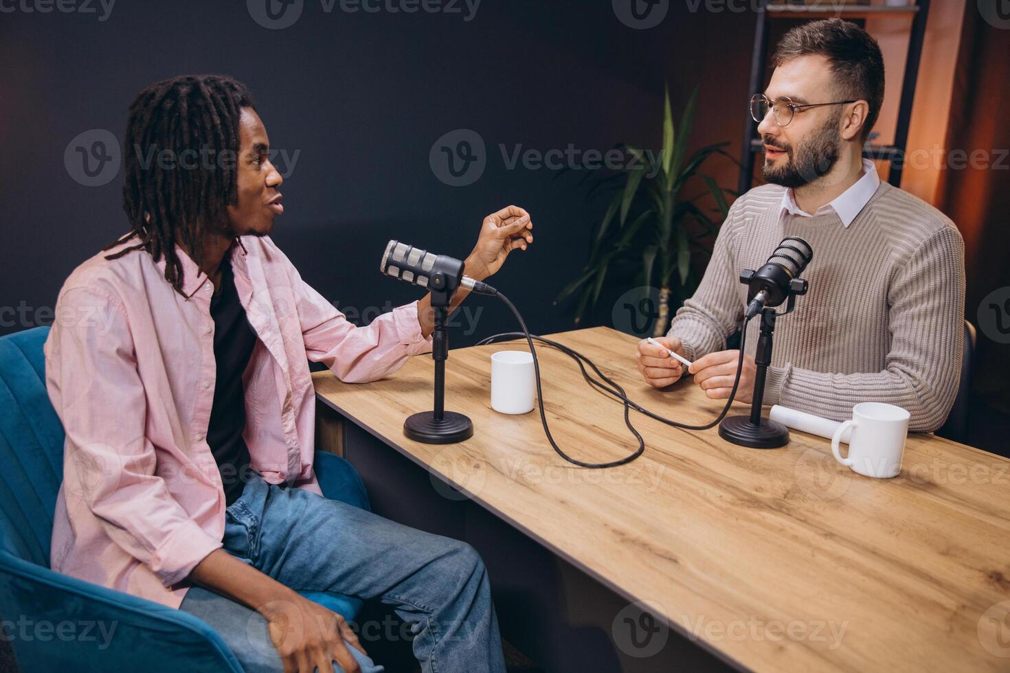 Two male podcasters having a conversation and recording a new podcast episode in a professional studio photo