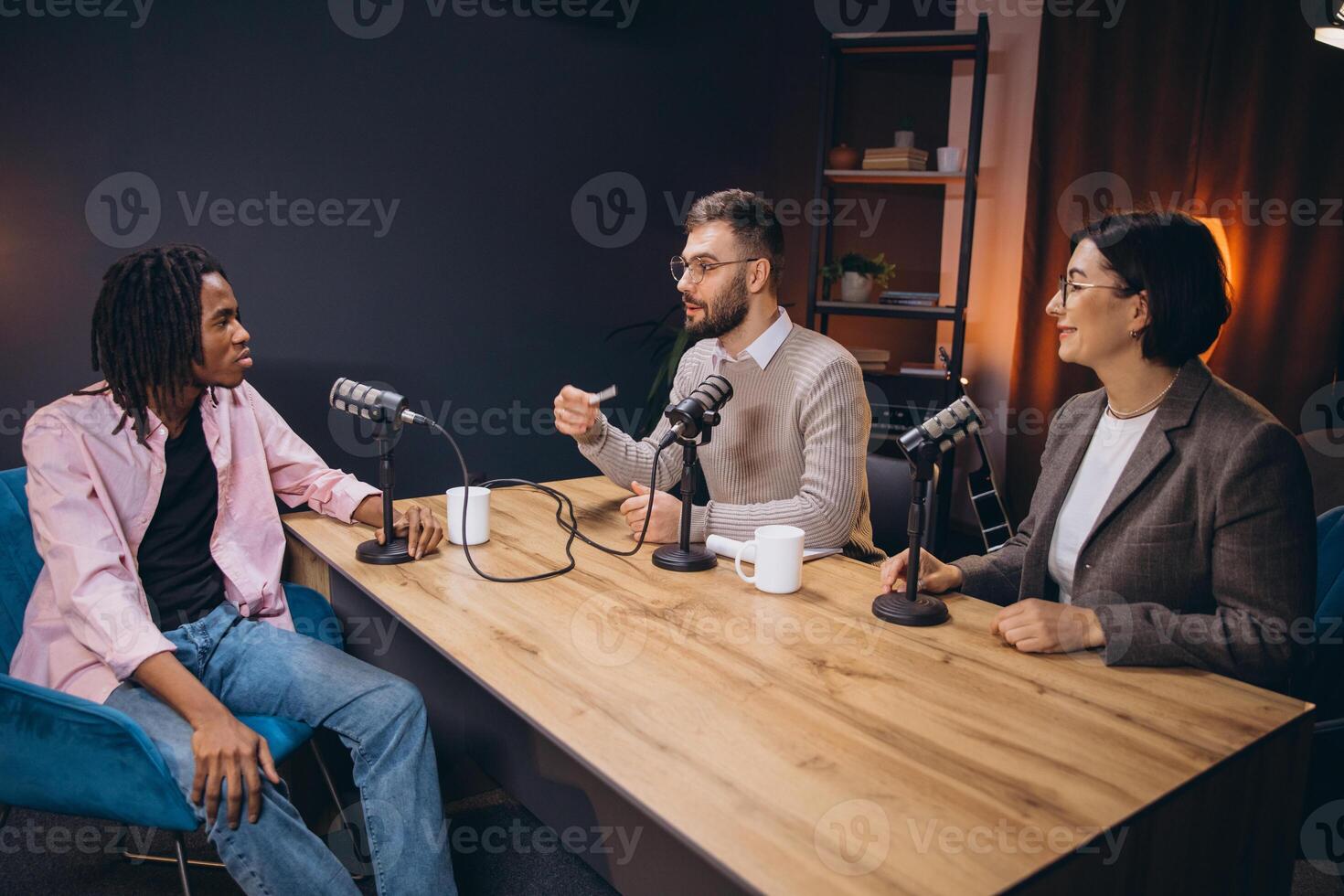 Podcasters recording audio content at wooden table inside professional studio setting photo