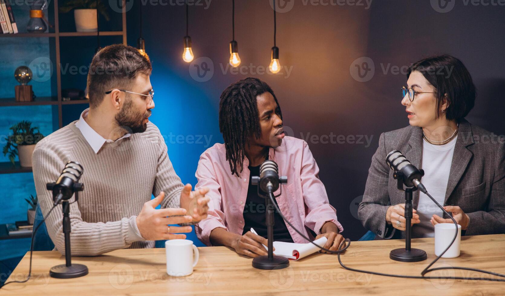Podcasting team collaborating, speaking into microphones while exchanging professional insights during live recording session photo