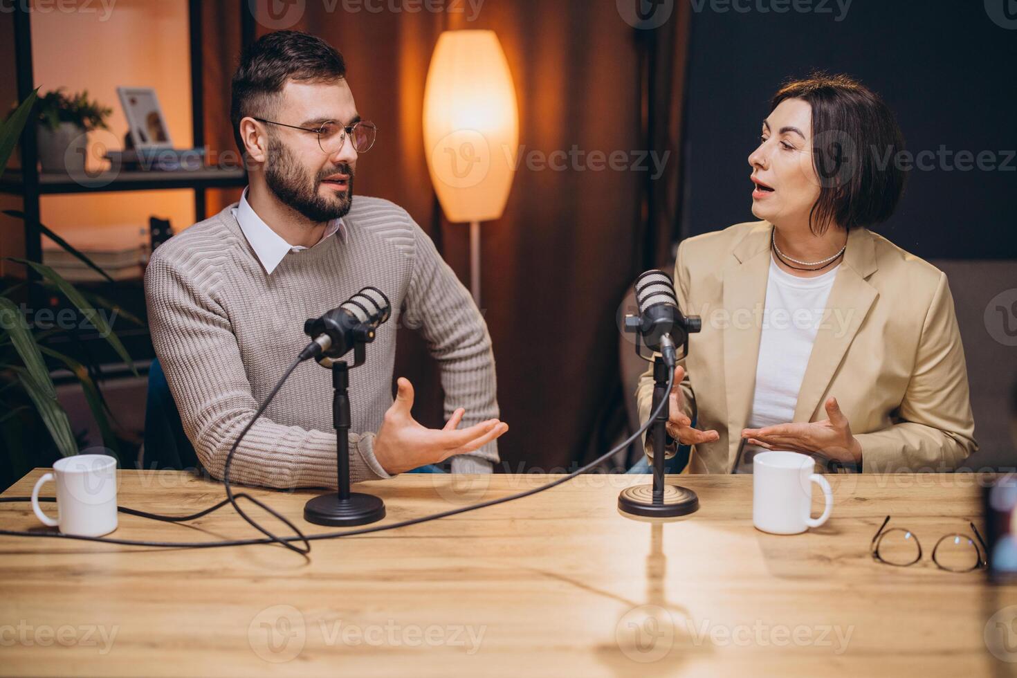 Podcasters collaborating in professional recording studio, speaking into microphones while sharing engaging discussion and creative insights photo