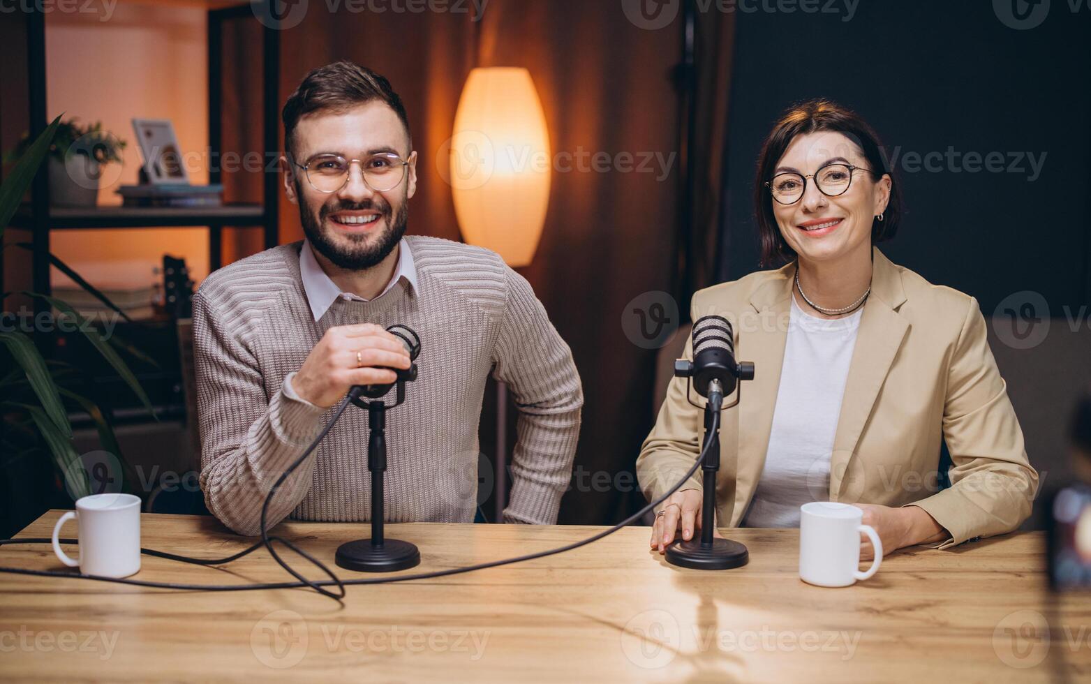 Two smiling podcasters engaging in lively conversation while recording audio content in a professional studio setting photo