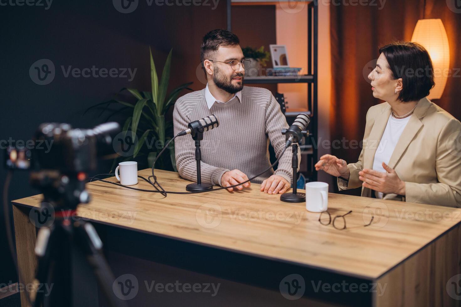 Two podcasters are recording a new episode in a professional studio, engaging in conversation and sharing their expertise photo