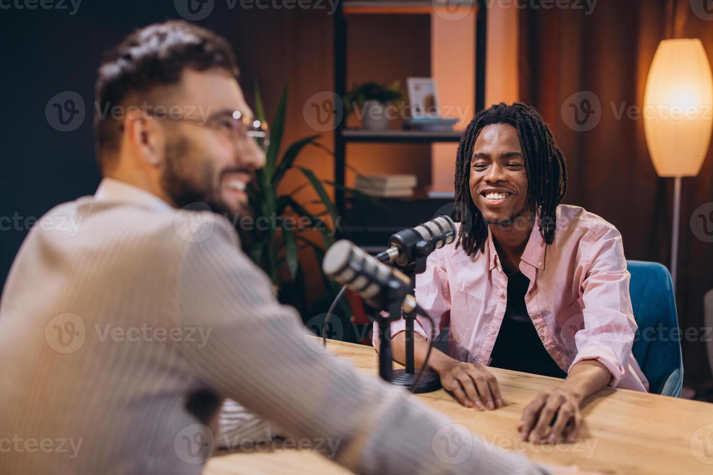 Two male podcasters smiling and talking during a recording session in a professional studio photo