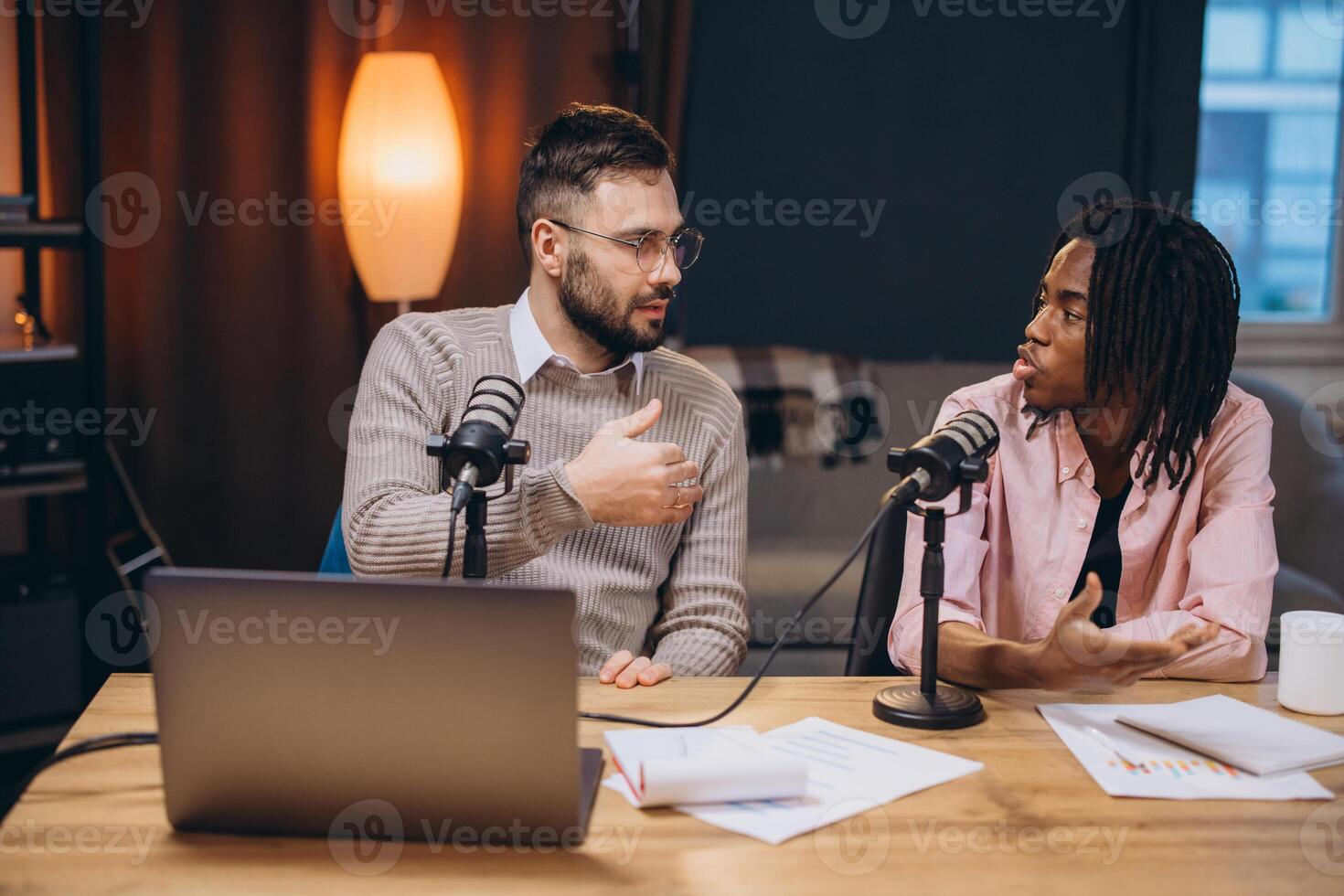 Two male podcasters having a conversation and recording a new episode in a professional studio photo