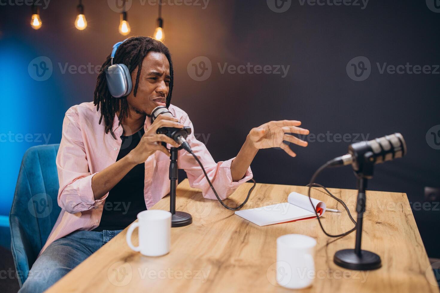 African American Professional radio host speaking passionately into microphone, gesturing dynamically during podcast recording in soundproof studio environment photo