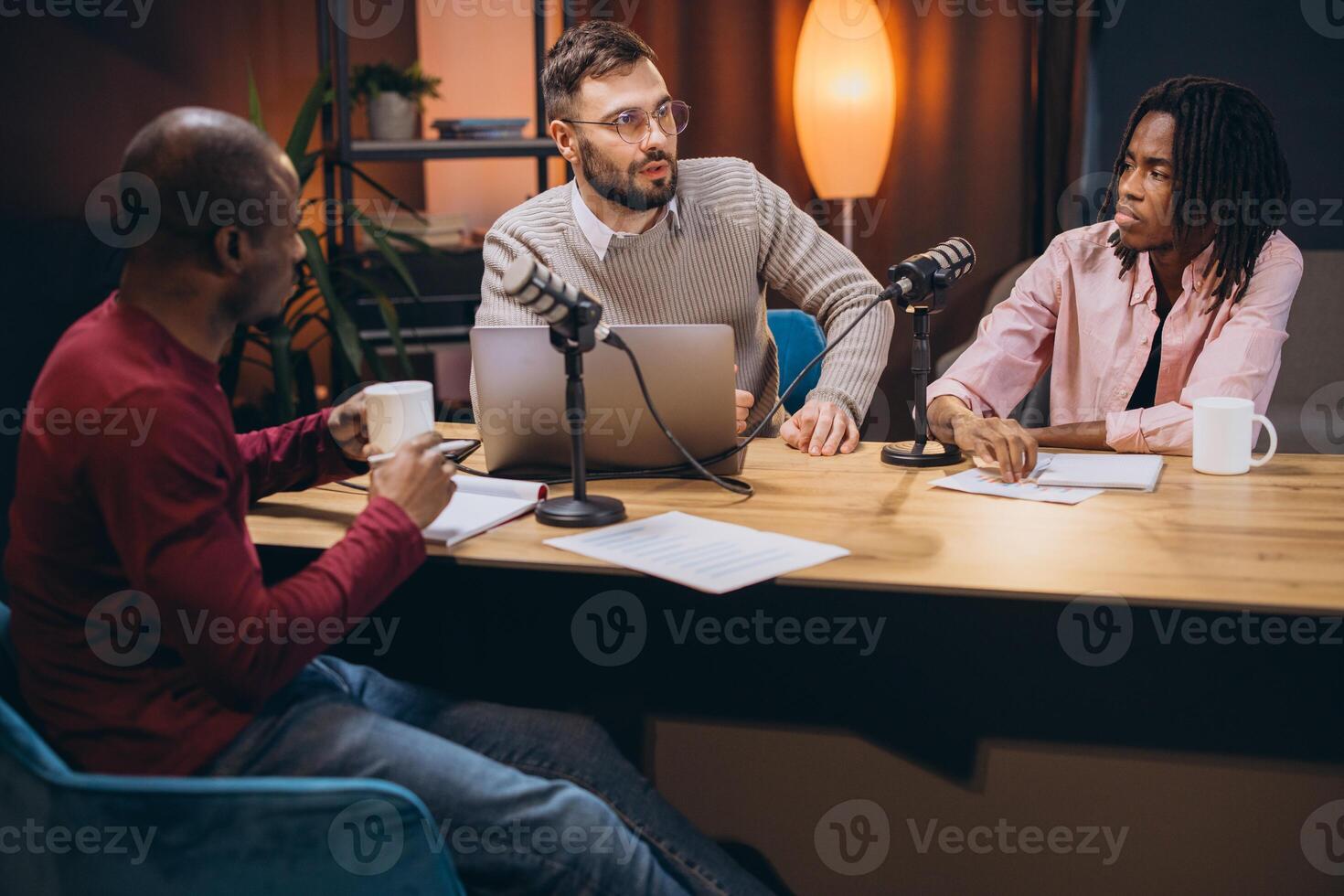 Three radio hosts recording a podcast in a professional studio, engaging in discussion and sharing insights with their audience photo