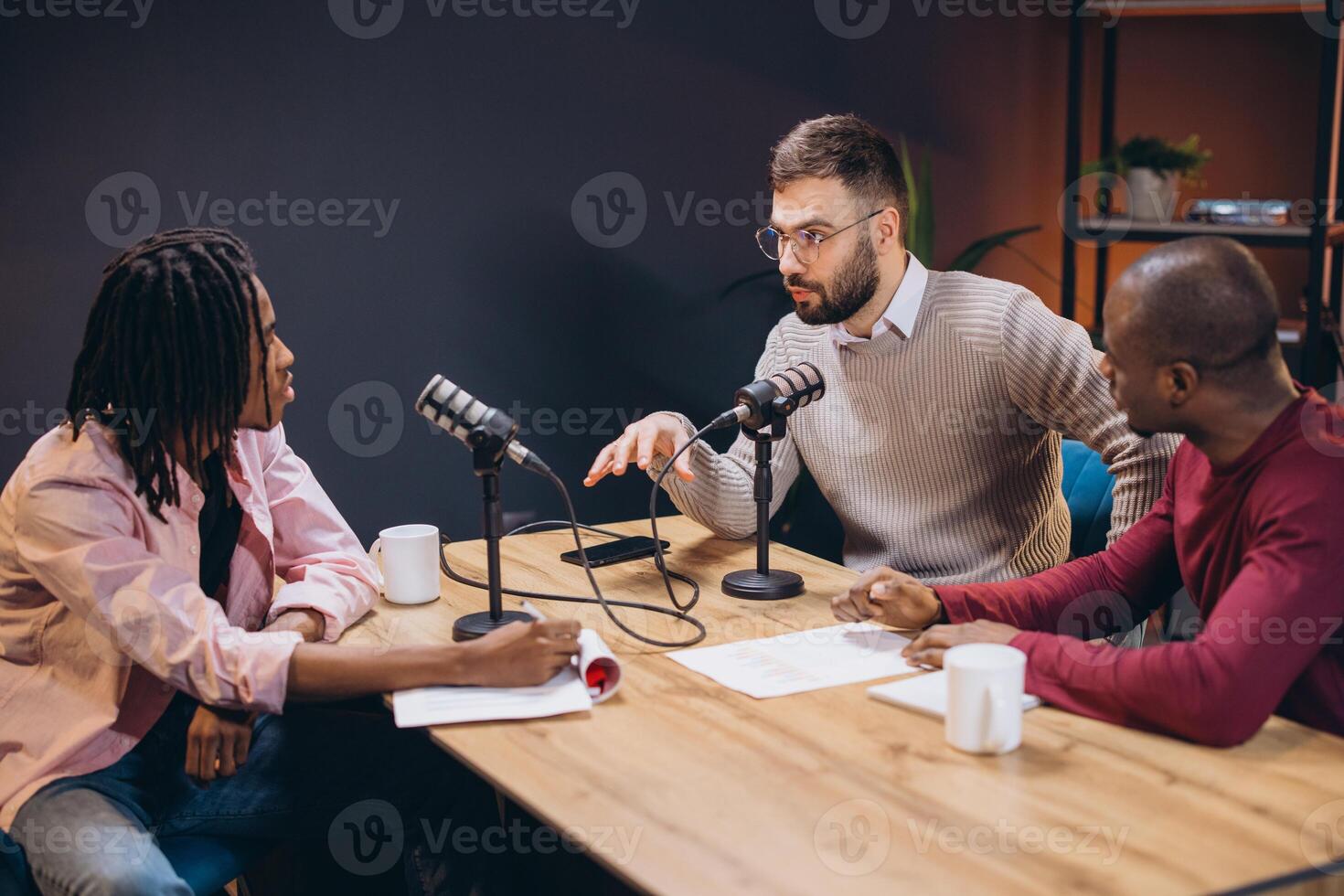 Three radio hosts interviewing a guest in a professional recording studio, discussing and sharing ideas during a podcast episode creation photo