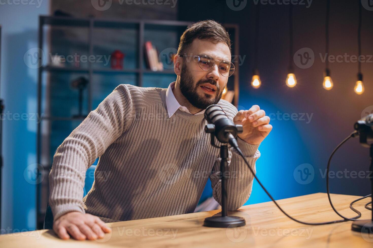 Young man speaking into a microphone while recording a podcast episode in a modern studio photo