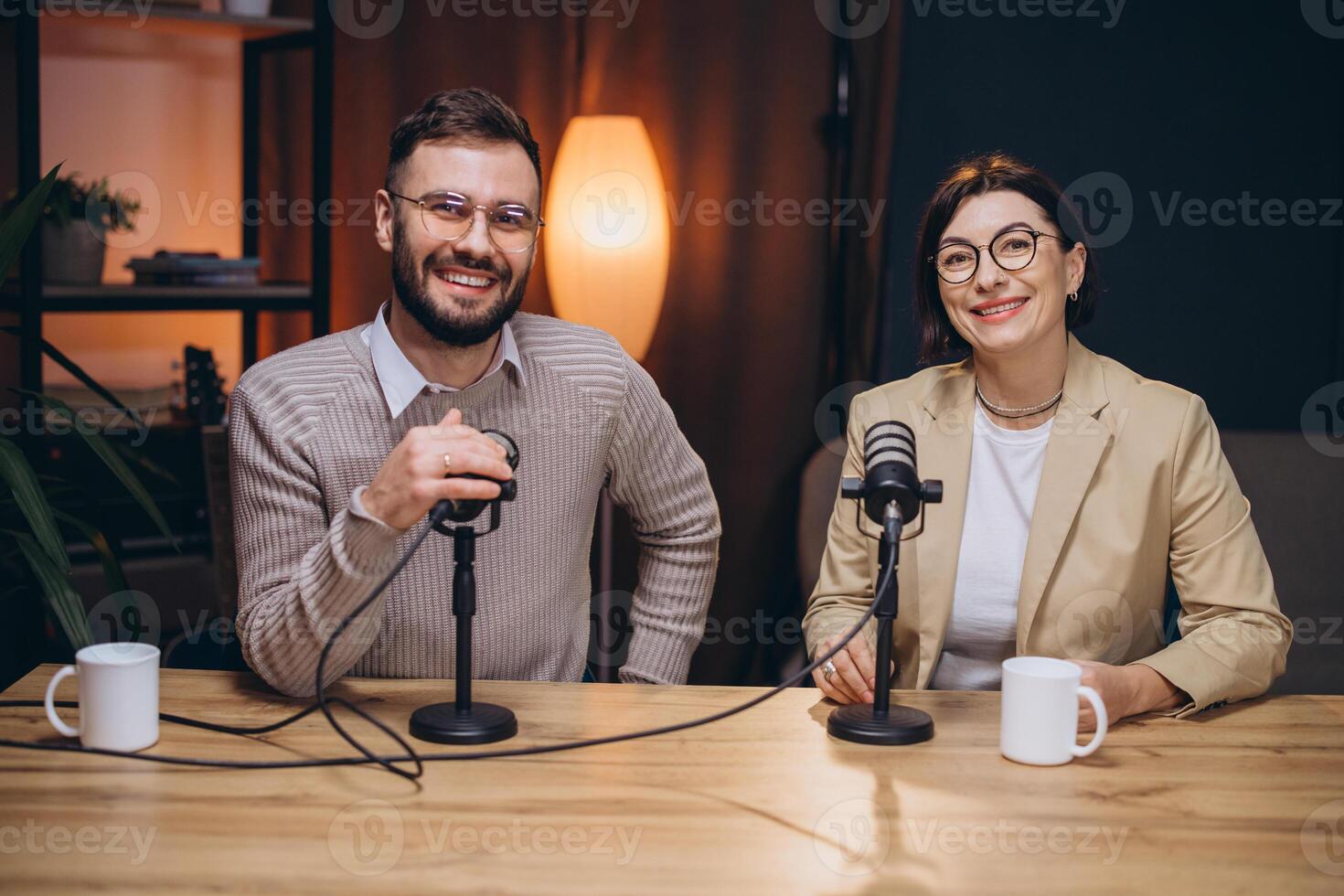 Two smiling podcasters recording audio content in a studio, using microphones and headphones photo