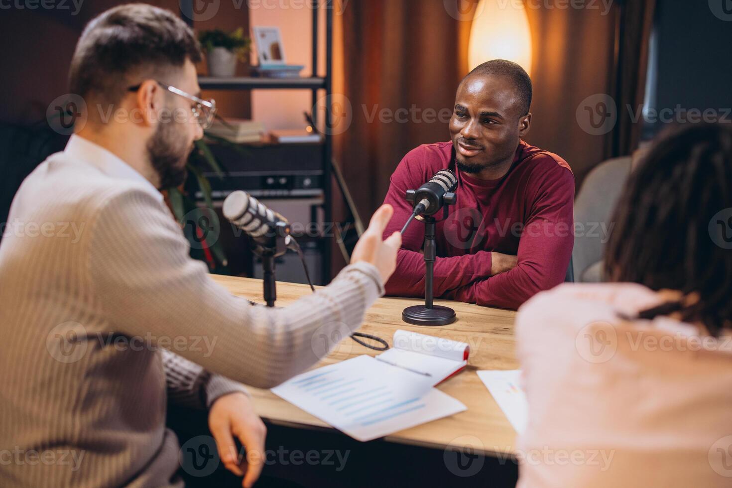 Two radio hosts interviewing a guest in a professional podcast studio, discussing and recording audio content photo