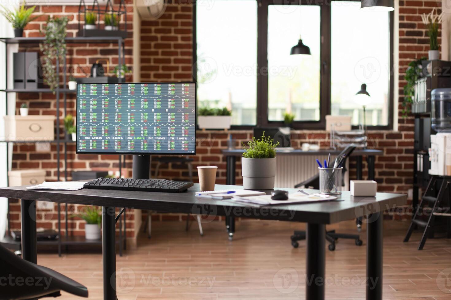 Computer screen displaying financial documents sits on spacious desk in startup workspace. Desktop pc on office table with screen showing business analytics in vacant brick wall room. photo
